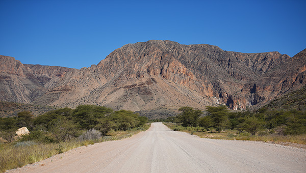 Gravel road winding between mountains on a Namibian road trip