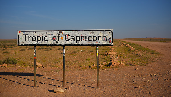 Open travel guidebook and map on the bonnet of a car in Namibia