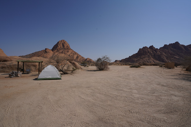 The Elegant Desert Lodge at dusk, thatched rooms against the Namibrand plains